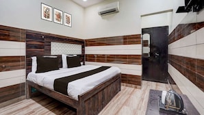 A modern bedroom with a wooden bed frame, a flat-screen TV, and a bathroom with a mirror and dark wood paneling. - Hotel O Mathura Janam Bhumi Link Road (Mathura)