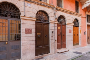 A row of traditional European-style buildings with arched doorways and numbered windows. - Elegant estate overlooking Piazza Erbe (Verona)