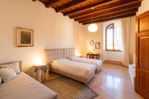A bedroom with two beds, a sofa, a round table, and a mirror. - Noble residence overlooking Piazza Erbe (Verona)