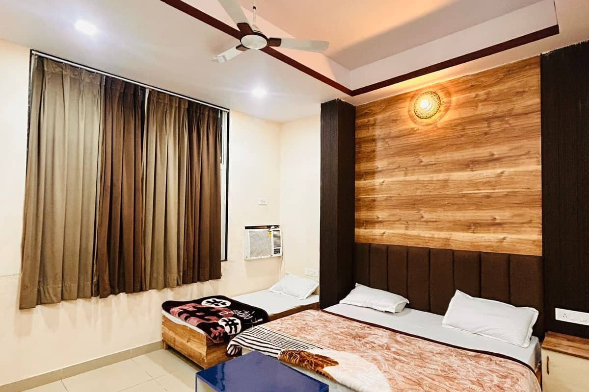 A bedroom with a bed, a desk, a chair, a ceiling fan, and a window with curtains.