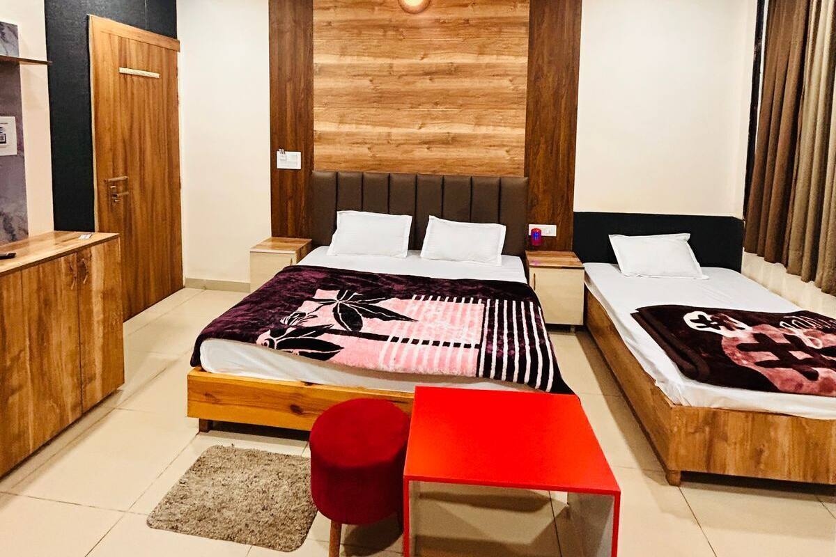A bedroom with a bed, a desk, a chair, a table, a ceiling fan, and a wall-mounted light.