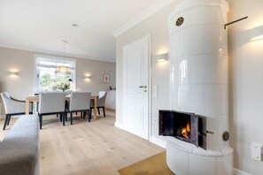 Ein modernes Wohnzimmer mit Kamin, einer Essecke mit Stühlen und Tisch, sowie einer Couch.