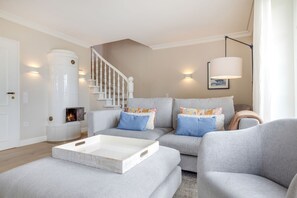 Ein modernes Wohnzimmer mit Kamin, grauen Sofas, einem Couchtisch und einer Treppe.