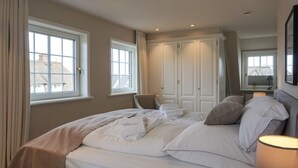 Een slaapkamer met een bed, een stoel, een kledingkast en een raam.