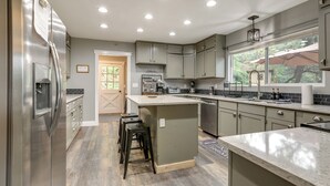 Una cocina moderna con un refrigerador de acero inoxidable, una isla grande y un ventanal con sombrilla.