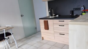 Eine Küche mit hellen Holzschränken, einer schwarzen Arbeitsplatte und einem weißen Stuhl.