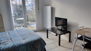 Ein Schlafzimmer mit Bett, Fernseher, Schreibtisch und Stuhl.