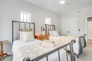 A bedroom with two beds, a nightstand, a dresser, and a ceiling fan.