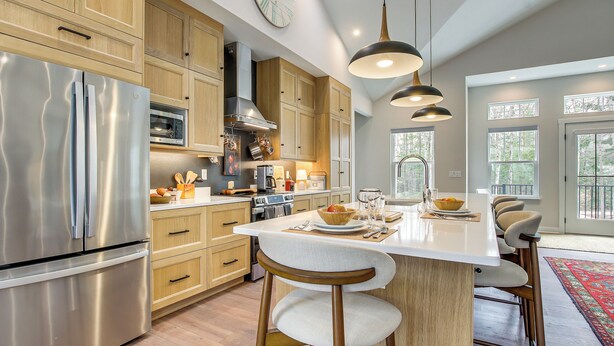 A modern kitchen with stainless steel appliances, wooden cabinets, and a central island with bar stools. - ADA-Compliant! 'Birch Haven' in Baileys Harbor (Baileys Harbor)
