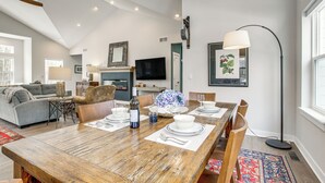 A spacious living area with a dining table set for four, a sofa, a television, and a floor lamp. - ADA-Compliant! 'Birch Haven' in Baileys Harbor (Baileys Harbor)