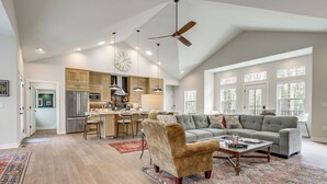 A spacious living area with a sofa, armchair, and coffee table, a kitchen with modern appliances, and large windows. - ADA-Compliant! 'Birch Haven' in Baileys Harbor (Baileys Harbor)
