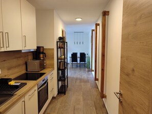 Eine schmale Küche mit modernen Geräten, einer Holzauskładung und einem Essbereich mit Tisch und Stühlen.