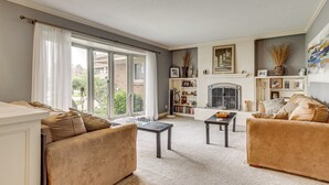 A living room with a fireplace, two sofas, a coffee table, and a bookshelf. - Backyard Oasis w/ Hot Tub & Greenhouse! Toledo Gem (Toledo)