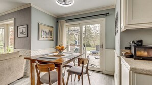 A dining area with a wooden table and chairs, a framed picture on the wall, and a view through the glass door. - Backyard Oasis w/ Hot Tub & Greenhouse! Toledo Gem (Toledo)