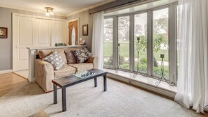 A living room with a sofa, a coffee table with chess pieces, a window with curtains, and a view of the outdoors. - Backyard Oasis w/ Hot Tub & Greenhouse! Toledo Gem (Toledo)