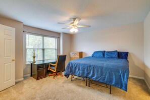 Ein Schlafzimmer mit Bett, Schreibtisch, Stuhl und Deckenventilator.