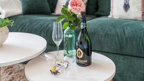 Et rundt hvidt bord med en champagneflaske, et glas og en vase med en blomst.