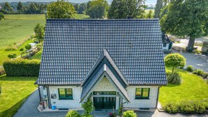 Et toetagers hus med et stejlt tag, en veranda og en velplejet græsplæne.