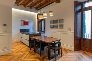 Eine moderne Küche mit Esstisch aus Holz, Pendelleuchten und Blick auf die Stadt.