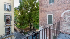 Un immeuble à plusieurs étages, avec une façade en briques, un balcon et un arbre devant.