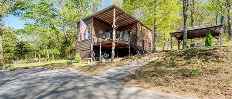 A cabin with a porch, a flag, and a covered area.