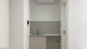 A compact kitchen with a sink, cabinets, and an air conditioning unit.