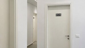 A hallway with a 'STAFF ROOM' sign on a door, white walls, and a tiled floor.