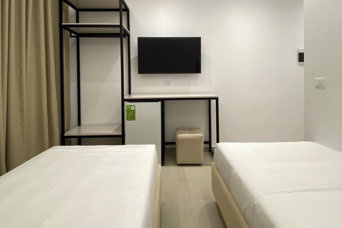 A hotel room with bunk beds, a desk, a television, and a small stool.