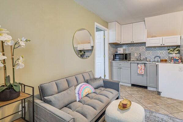 A living room with a grey sofa, a round mirror, and a potted orchid. - 12 Mi to Nat'l Mall: Cozy Apt w/ Shared Patio (Springfield)