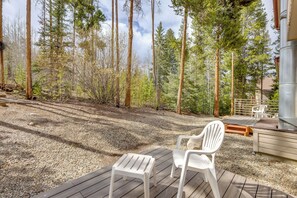 Une terrasse avec deux chaises blanches, un barbecue et une vue sur une forêt.
