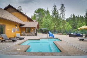 A pool area with lounge chairs, a covered seating area, and a wooden cabin. - Whitefish Lake Couples Escape w/ Community Perks! (Whitefish)