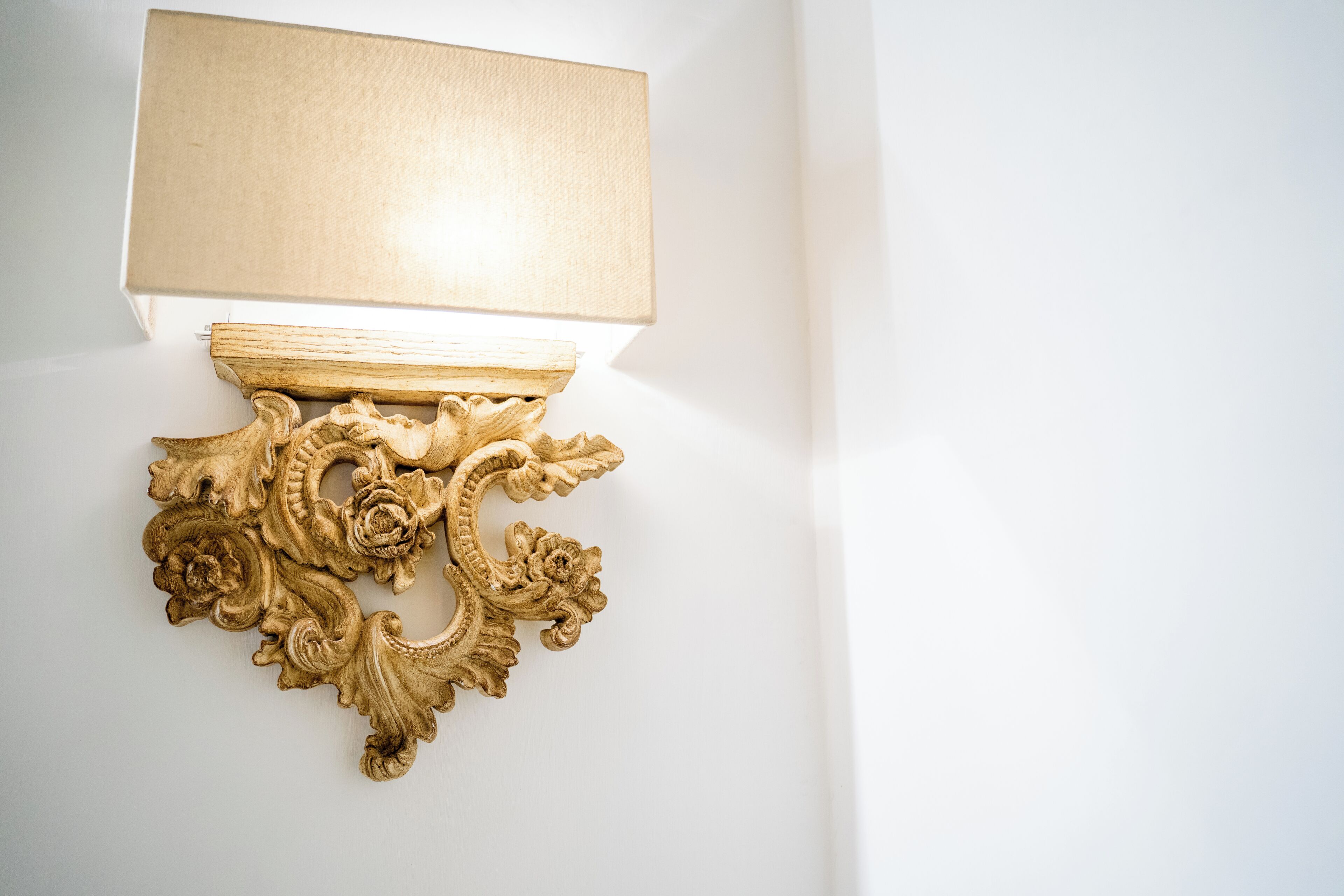 A wall-mounted light fixture with an ornate, gold-colored design.