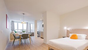Une chambre d’hôtel moderne équipée d’un lit, d’une table de chevet et d’un coin repas avec des chaises et une table.