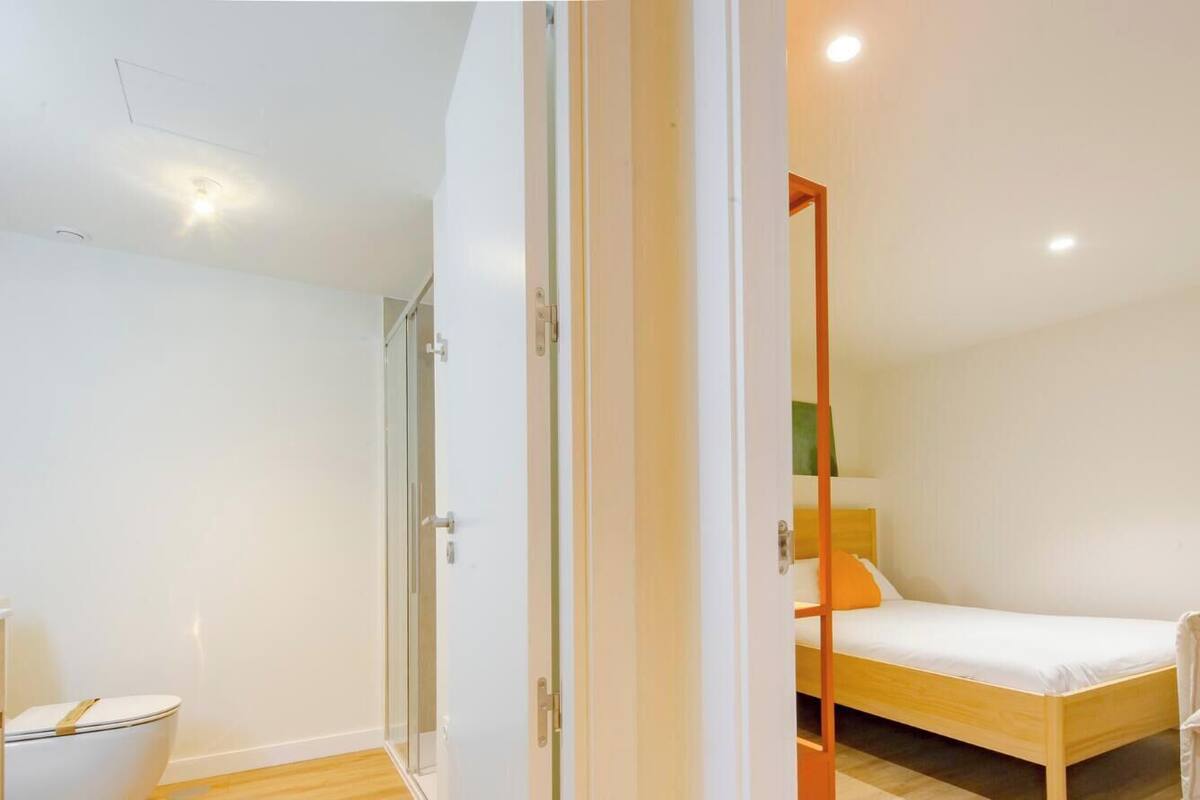 Un dormitorio con una cama de madera, un sofá blanco y una mesita de noche.