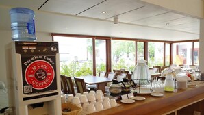 Een koffiehoek met een waterdispenser, theemachine en diverse koffiezetapparatuur.