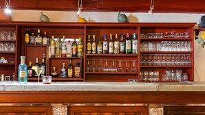 Un espace bar avec des étagères remplies de bouteilles d’alcool et de verres.