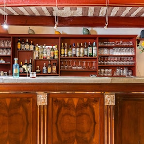 Zona de bar con estantes llenos de botellas de licor y copas.