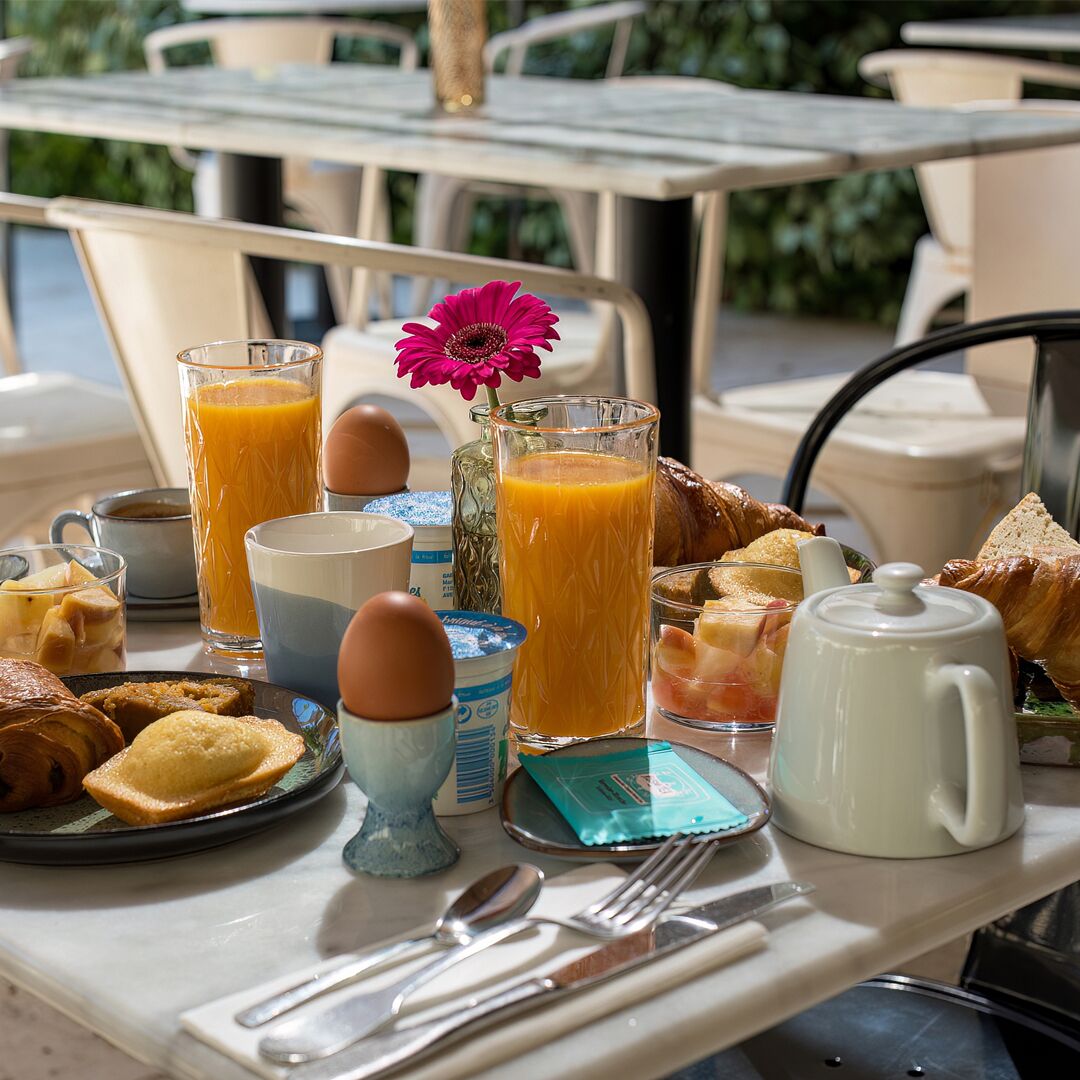 Una mesa de desayuno con diversos alimentos, bebidas y utensilios.