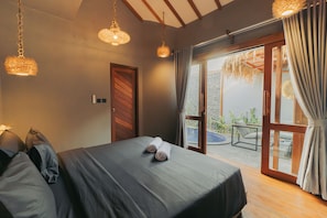 A bedroom with a bed, a wooden door, and a view of the outdoors. - Gili Nomade Villas (Gili Trawangan)