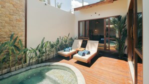 Un área de piscina con sillones de descanso, un jacuzzi y plantas tropicales.