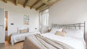A bedroom with two beds, a wooden ceiling, a painting, and a window with curtains. - Preseglie Lake Garda - Rosa Canina (Desenzano Del Garda)