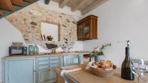 Eine rustikale Küche mit Steinwand, Holzschränken, einem Vintage-Toaster und einer Weinflasche.