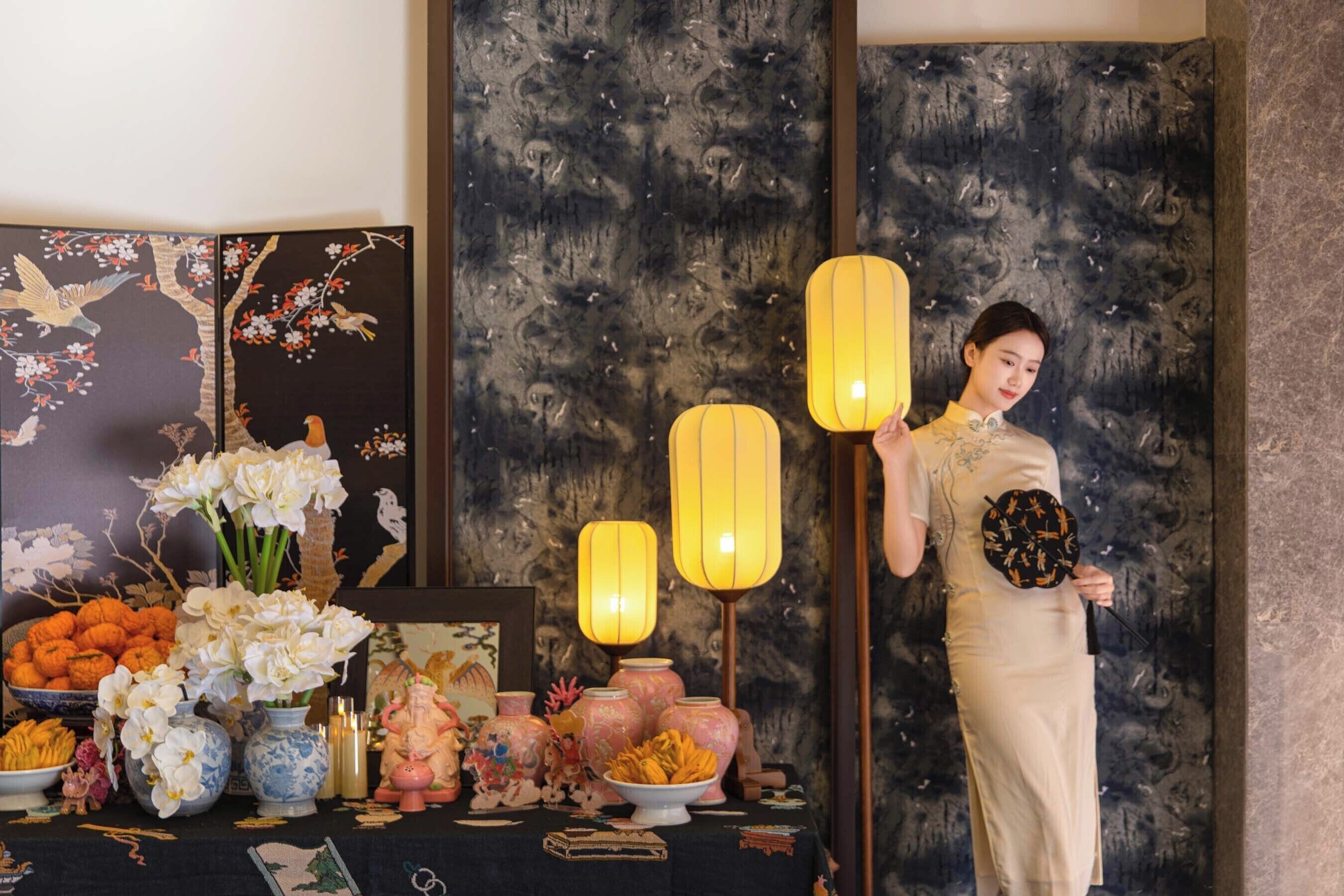 A room with a traditional Asian-style decor, including a table with various items and a person standing by.