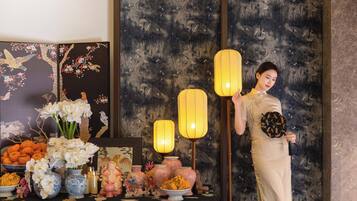 A room with a traditional Asian-style decor, including a table with various items and a person standing by.