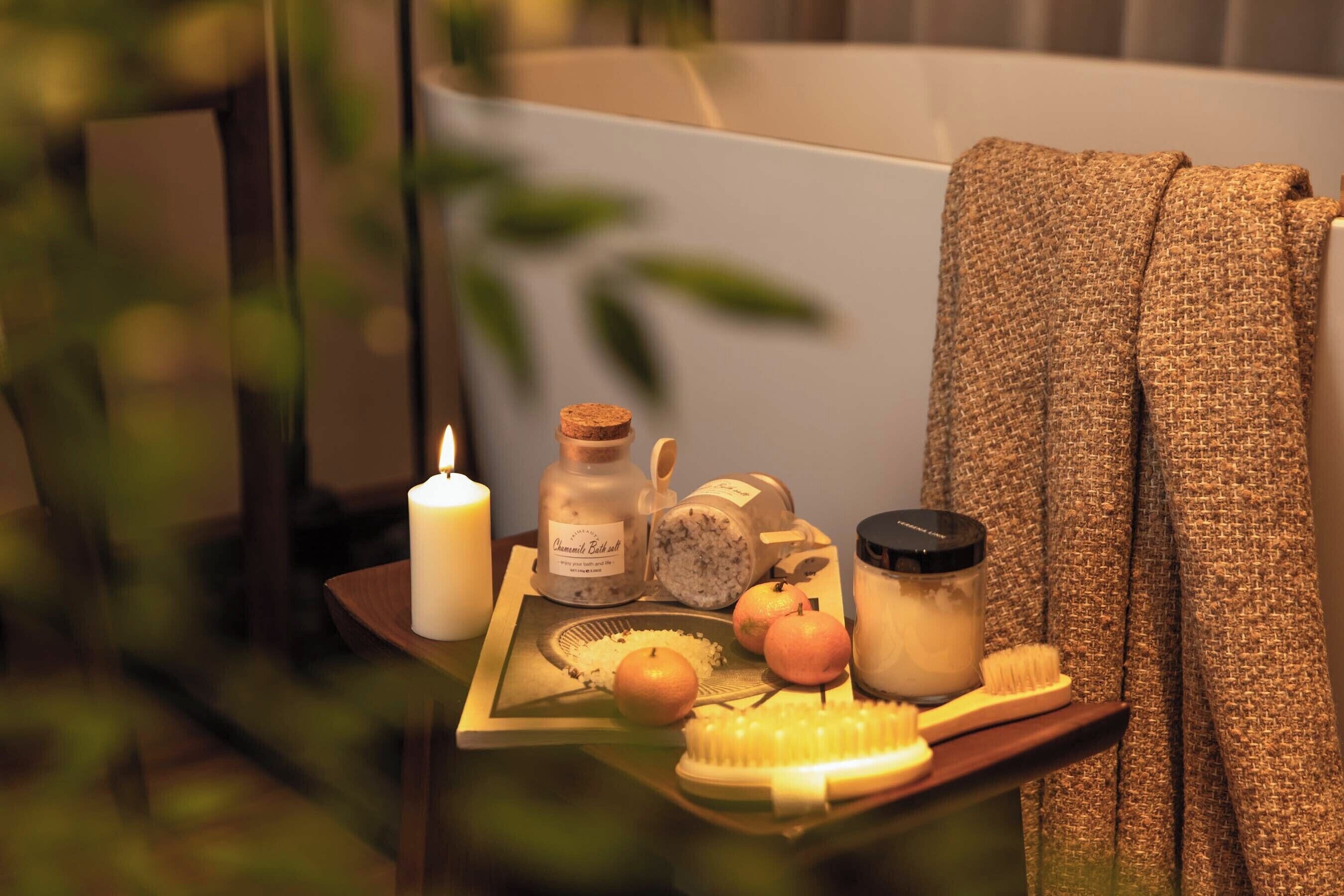 A tray with candles, a bottle, a jar, and a brush on a table.