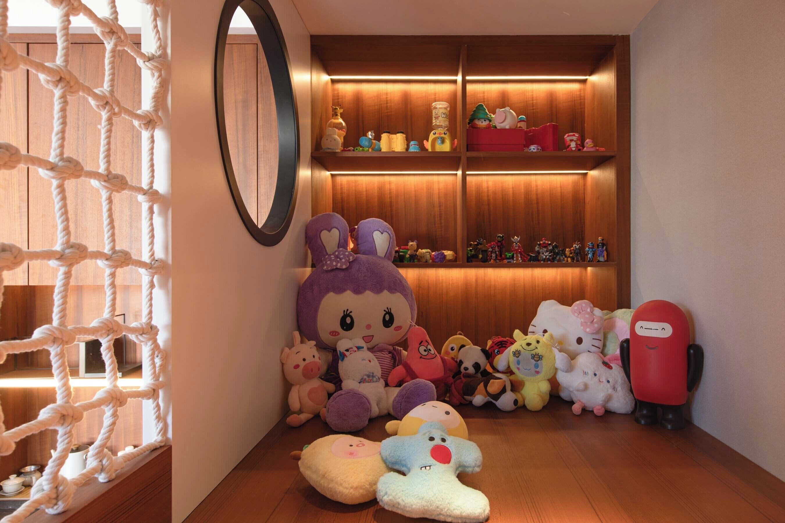 A room with a rope wall, plush toys, and a shelf with various items.