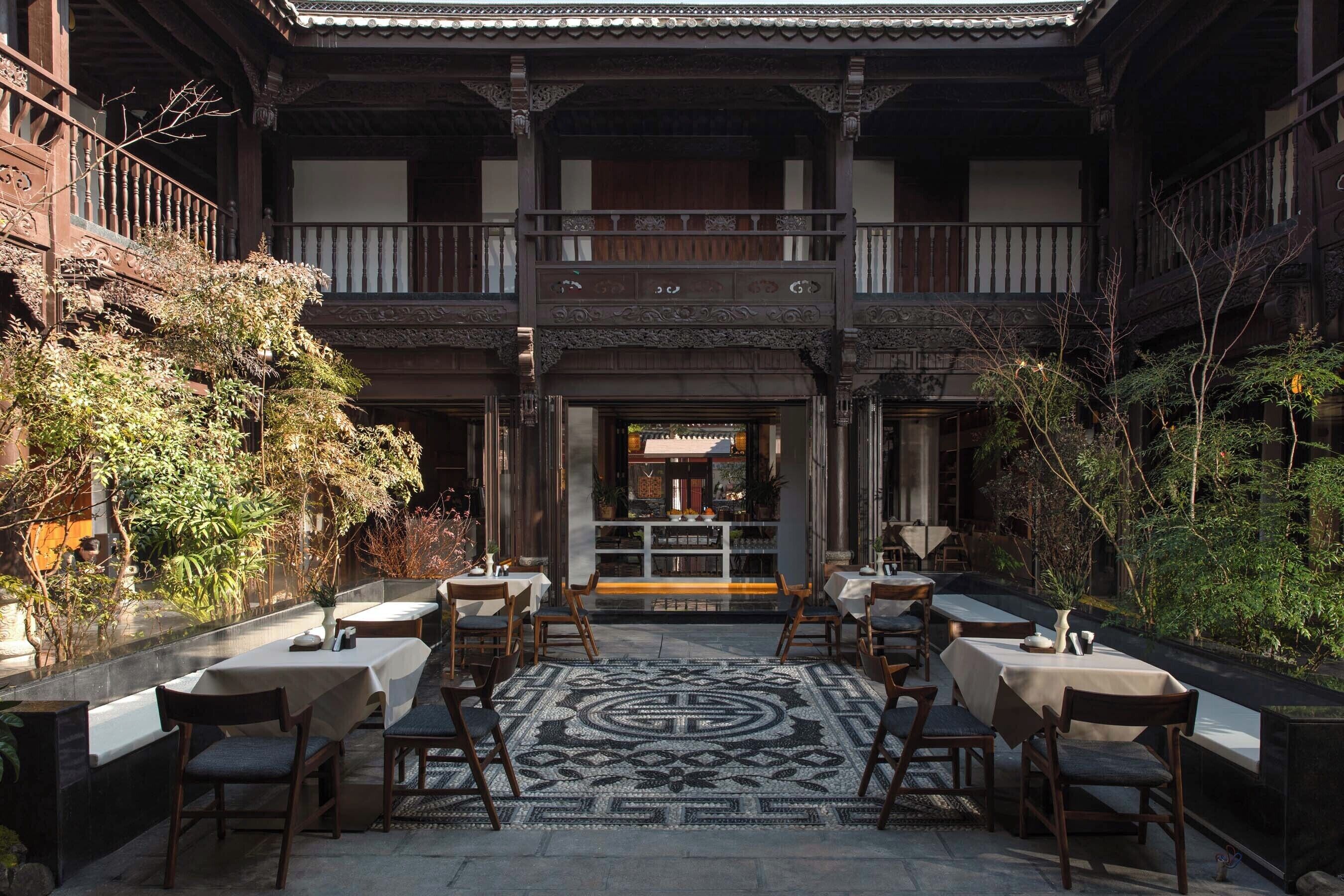 A traditional Japanese-style courtyard with tatami mat flooring, wooden tables, and chairs arranged for dining.