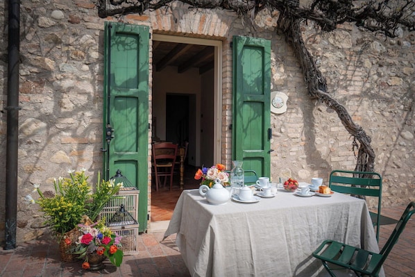 Una mesa preparada para tomar té, con vistas a un edificio de piedra y contraventanas verdes.