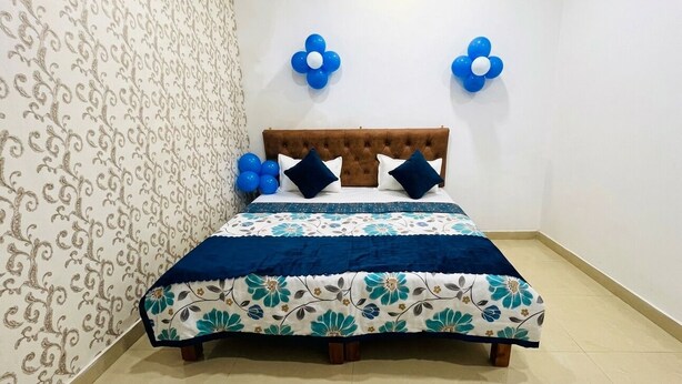 Ein Schlafzimmer mit einem gesteppten Kopfteil, einem blumigen Bettbezug und blauen Wanddekorationen.