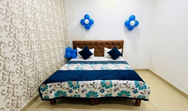 Une chambre à coucher avec une tête de lit capitonnée, une couvre-lit à motifs floraux et des décorations murales bleues.